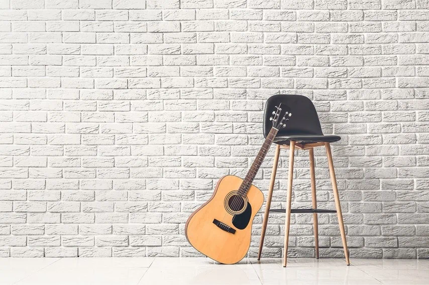 アコースティックギターを椅子に立てかけている写真