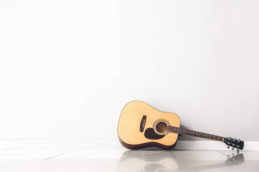 アコースティックギターを床に置いている写真