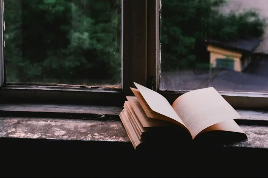 窓際で本を開いている画像