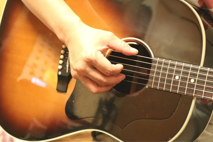 アコースティックギターを指で弾いてるところ
